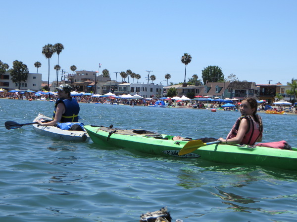 Two people in a kayak with people celebrating